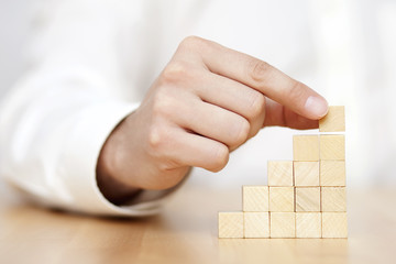 Man's hand put wooden blocks in the shape of a staircase. Business success concept. 