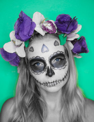 Closeup face of woman with Mexican sugar skull makeup and flowery wreath looking into the camera. Creative, artistic, Halloween concept