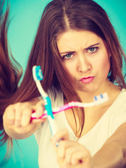 Woman holding two toothbrushes crossed