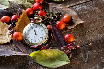 The old clock on the background of autumn leaves and berries of hawthorn