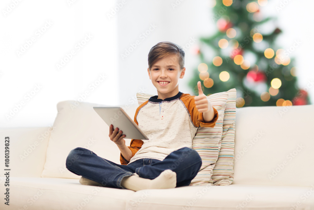 Wall mural boy with tablet pc showing thumbs up at christmas