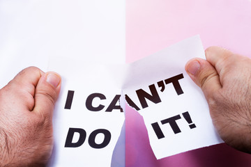 Man cutting with scissors the piece of paper with words I can't do it.