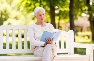 senior woman reading book at summer park