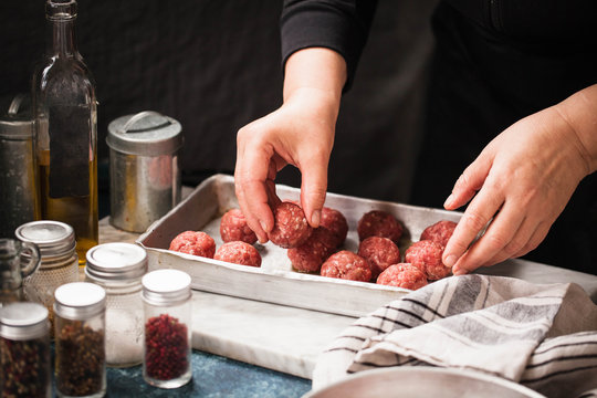Tray of raw meatballs being prepared by a cook