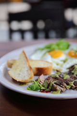 Grilled beef steak with toast , fried egg and vegetables on top with pesto sauce