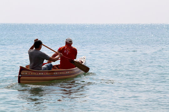 Two man boating in handmade canoes of wooden planks on Black sea