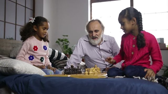 Grandfather teaching grandchildren chess at home