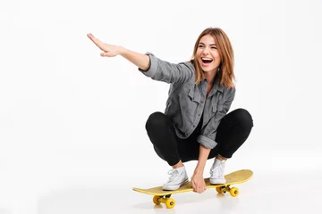 Fotobehang Skateboard Portrait of a happy cheerful girl riding a skateboard  © Drobot Dean