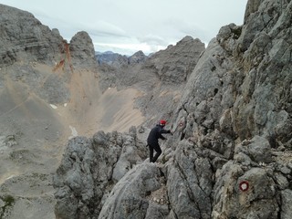 Man on via ferrata at on the way up to Škrlatica 2,740 m with trail marks on the rocks.