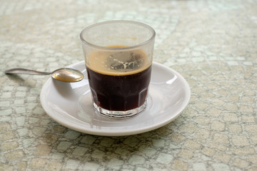 A glass of coffee and a spoon.