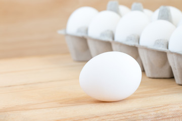 Close-up of raw chicken eggs in egg box on wooden background
