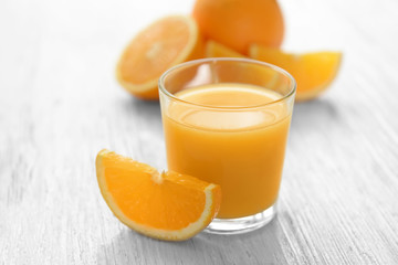 Glass of fresh orange juice with slice on wooden table