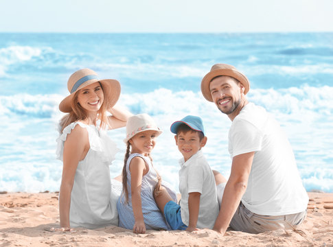 Happy family sitting on sea beach at resort