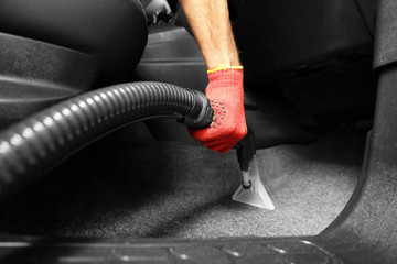 Male worker using vacuum cleaner in car