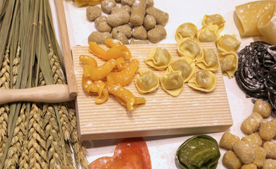 Fototapeta premium cutting board with ravioli and fresh pasta with black cuttlefish