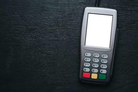 Top view to credit card terminal on dark wooden desk. Mockup witn clear white mockup screen template