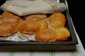 hot pies on a baking sheet covered with a napkin black background