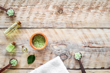 Spa salt and lotions for skin with tea tree oil on rustic wooden background top view pattern copyspace