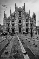 Fototapeta premium Black and white view of tourists in the Piazza Duomo square in front of Milan Cathedral church
