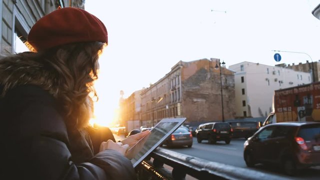 Young attractive girl with tablet in the sunset in the city. lifestyle portrait of young female using smart phone tablet for social media networking
