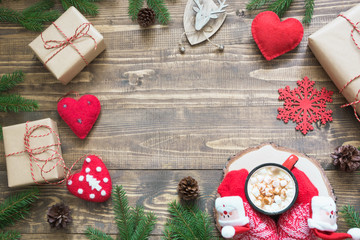 Christmas composition with giftbox, deer, red hearts and decor on wooden board with copy space. Top view.