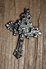 silver cross with a jesus on wooden background