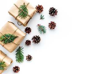 Gifts for new year wrapped in craft paper near spruce branches and cones on white background top view copyspace