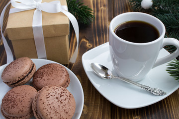 Coffee, macaroons and Christmas gift on the wooden background