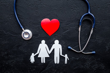 Choose health insurance. Stethoscope, paper heart and silhouette of family on black stone background top view