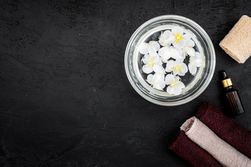 Bath in bowl with tropical flowers for foot spa on black background top view copyspace