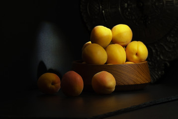 Yellow apricots on a black background in a beam of the sun