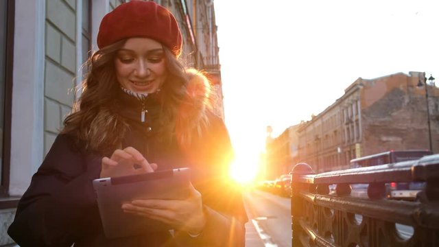 Young attractive girl with tablet in the sunset in the city. lifestyle portrait of young female using smart phone tablet for social media networking