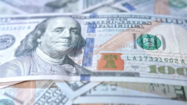 A pile of hundred dollar banknotes on a table. Close-up dolly shot