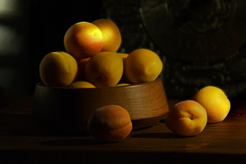 Yellow apricots on a black background in a beam of the sun