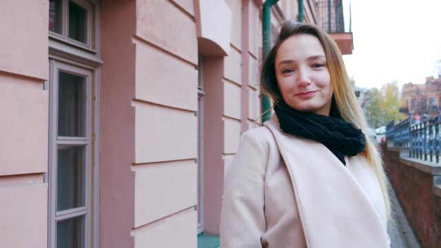 Beautiful young girl with an attractive appearance, adorable look, scarf and autumn coat in the city. Amazing view of business lady walking down the city street.