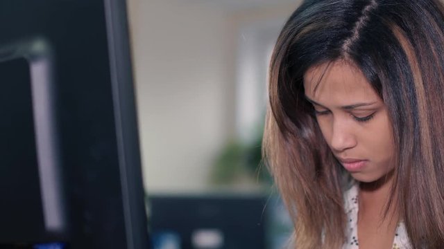 Beautiful girl of mixed race, intently working at the computer
