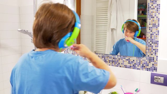 Happy kid dancing while washing teeth listening music doing dub gesture closeup