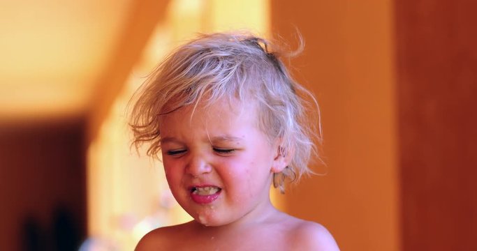 Portrait of baby boy getting a bite from healthy fruit but then doing an expression of digust to what he is eating