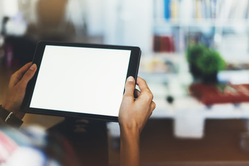 Hipster girl using tablet technology in home atmosphere, holding computer with blank screen on background bokeh, female hands texting on holiday, mockup templates gadget, lifestyle concept