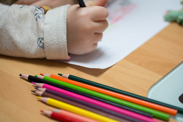 Kind malt und bastelt mit Buntstiften und Schere in Kindergarten,Schule und Hort