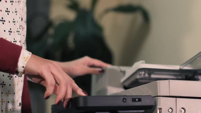 Young girl typing at office documents, pressing a button, turns on the printer