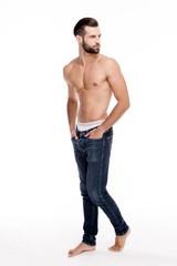Fototapeta premium Pure masculinity. Full length of handsome young man in jeans looking away while standing against white background.