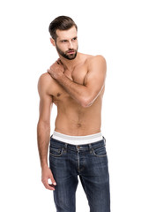 Fototapeta premium Sensual and handsome. Handsome shirtless young man in jeans looking away while standing against white background