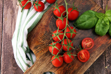Cherry tomatoes with basil and dish towl on cutting board.