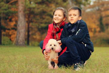 A boy with a girl is played with a dog in the park