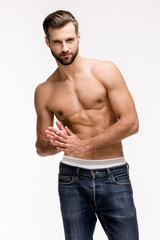 Fototapeta premium Gorgeous torso. Handsome shirtless young man in jeans looking at camera while standing against white background
