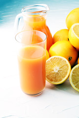 glass jar of fresh orange juice with fresh fruits on white table