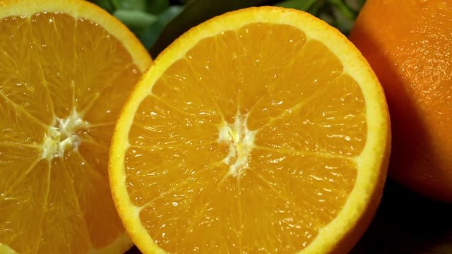 Orange fruit under water . Group of oranges with leaves on wooden boards. Orange cut in half. Camera moves from left to right. Cross section.