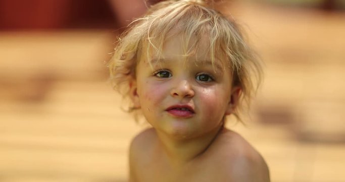 Portrait of bashful shy infant toddler looking at camera while eating a pear fruit - 4k clip resolution
