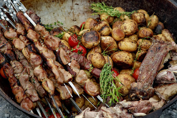 freshly prepared shish kebab with baked potatoes and vegetables and spices